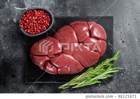 Beef veal kidney, raw offal meat on marble board with rosemary. Black background. Top view 98125871