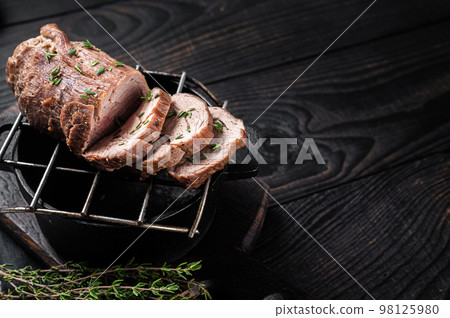 Roast beef on a grill, tenderloin sliced meat with herbs. Black Wooden background. Top view. Copy space Roast beef on a grill, tenderloin sliced meat with herbs. Black Wooden background. Top view. Copy space 98125980
