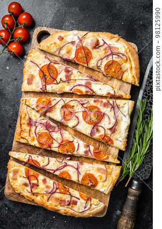 Homemade Flammkuchen or tarte flambee with cream cheese, bacon, tomato and onions. Black background. Top view 98125990