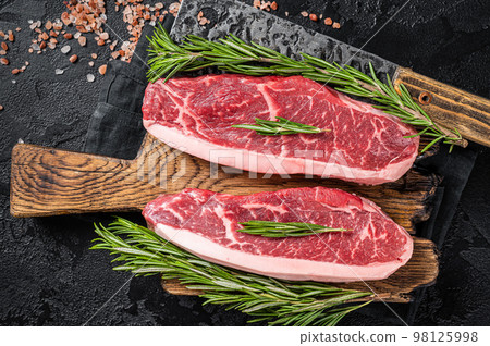 Raw cap rump beef meat steak or top sirloin on butcher board. Black background. Top view Raw cap rump beef meat steak or top sirloin on butcher board. Black background. Top view 98125998