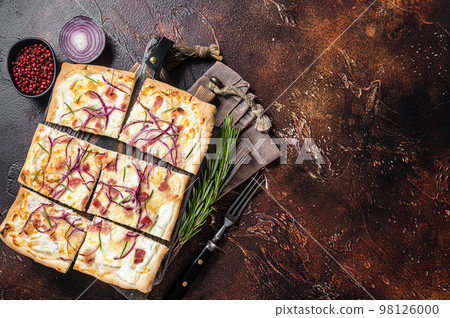 French tarte flambee with cream cheese, bacon and onions. Flammkuchen from Alsace region. Dark background. Top view. Copy space 98126000