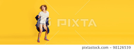 Banner with excited young man wearing bathrobe dancing isolated over bright yellow background. Positive emotions, home cozy atmosphere, funny meme emotions Banner with excited young man wearing bathrobe dancing isolated over bright yellow background. Positive emotions, home cozy atmosphere, funny meme emotions 98126539