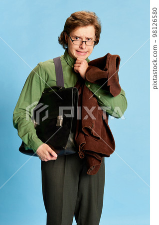 Cute charming young man, student or office clerk in vintage fashion style costume, suit posing isolated on blue background. Business, studying, fashion concept 98126580