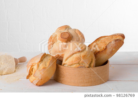 Fresh italian wheat breads in the sieve on the table with flour and dough on white background 98126769