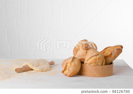 Fresh italian wheat breads in the sieve on the table with flour and dough on white background 98126780