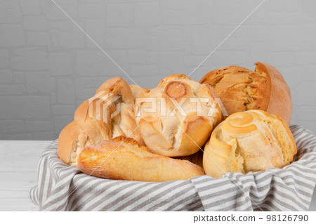 Fresh italian wheat breads in the basket on white wall background. 98126790
