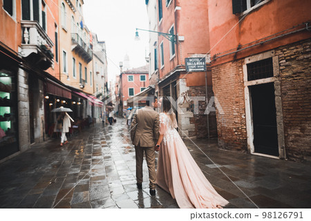 Beautiful bride and groom embracing and kissing on their wedding day outdoors Beautiful bride and groom embracing and kissing on their wedding day outdoors 98126791