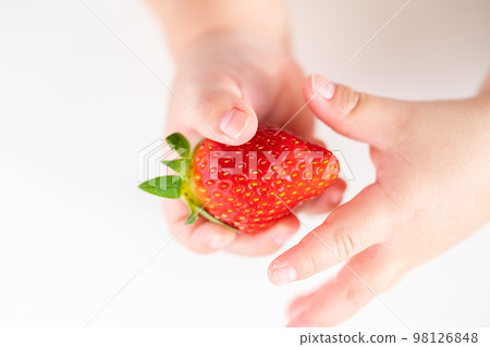 Infant's hand holding a strawberry. 98126848