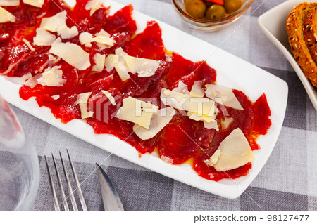 Appetizing raw veal carpaccio served with cheese 98127477