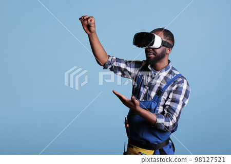 Experienced renovator using virtual reality goggles looking at plans for new kitchen project. Construction worker using vr headset against blue isolated background. Experienced renovator using virtual reality goggles looking at plans for new kitchen project. Construction worker using vr headset against blue isolated background. 98127521