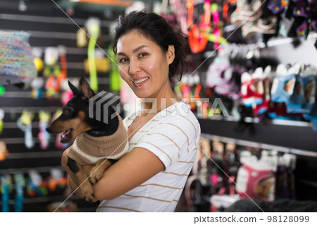 Oriental woman with her little dog in pet shop 98128099
