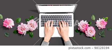 Woman using her laptop with pink roses 98128194