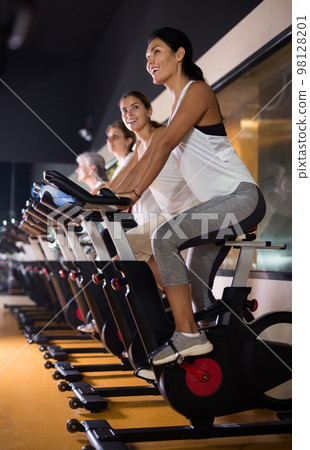 Woman on stationary bike workout in gym Woman on stationary bike workout in gym 98128201
