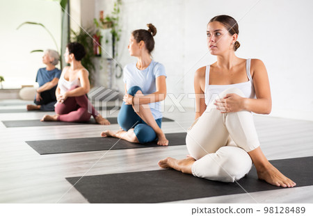 Group of sporty people practicing various yoga positions during training Group of sporty people practicing various yoga positions during training 98128489