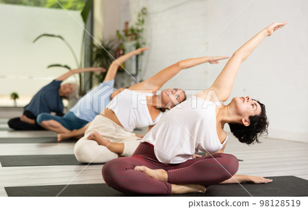 Attractive girl in sportswear using mat spend free time doing yoga for health and wellness together with group of people 98128519