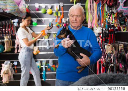 Old man choosing dog food in pet shop Old man choosing dog food in pet shop 98128556