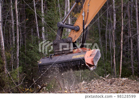Mulching attachment on excavator, being used to clear roadside brush. Mulching attachment on excavator, being used to clear roadside brush. 98128599