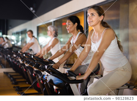 Woman taking indoor cycling class at gym 98128623
