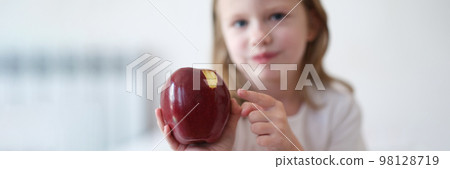 Girl child bites and eats big red apple Girl child bites and eats big red apple 98128719