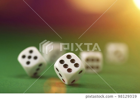 White dice on a green felt table with bokeh background 98129319