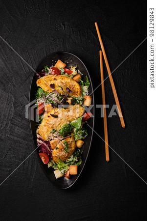 Cesare salad chopsticks in Japanese stile on a black concrete background. 98129843