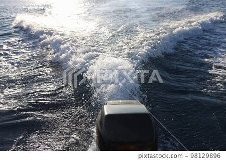 Boat engine and water trail with waves and foam behind it. Boat engine and water trail with waves and foam behind it. 98129896