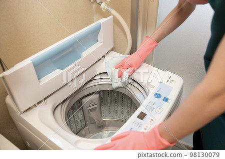 A woman's hands wiping down a washing machine A woman's hands wiping down a washing machine 98130079