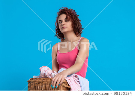 Totally tired girl carries heavy wicker basket with men's shirts. Totally tired girl carries heavy wicker basket with men's shirts. 98130184