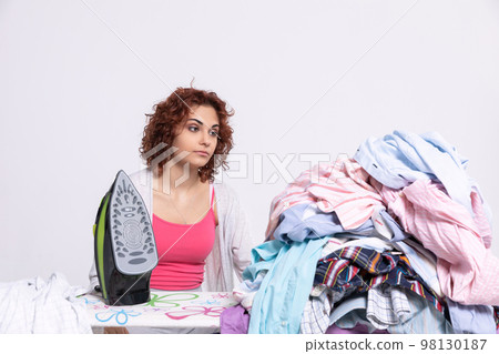 A large number of men's shirts to be ironed. The girl is resigned. A large number of men's shirts to be ironed. The girl is resigned. 98130187