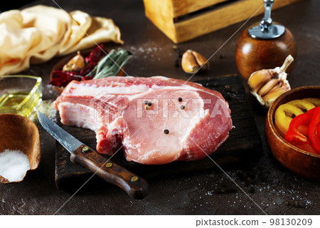 Raw pork meat. Fresh steaks on slate board on black background. Top view Raw pork meat. Fresh steaks on slate board on black background. Top view 98130209