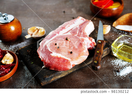 Raw pork meat. Fresh steaks on slate board on black background. Top view 98130212