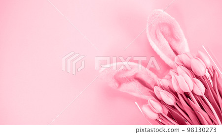 Fluffy bunny ears and fresh tulips flowers on pink background. Image is toned in Viva Magenta color of year 2023. Easter holiday concept. Space for text. Copy space. Top view, flat lay. Fluffy bunny ears and fresh tulips flowers on pink background. Image is toned in Viva Magenta color of year 2023. Easter holiday concept. Space for text. Copy space. Top view, flat lay. 98130273