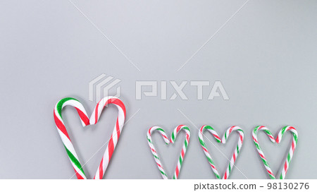 Red, green and white candy canes in the shape of heart on grey background. Valentine's Day concept. Greeting card with copy space for your text or advertising, flat lay. 98130276