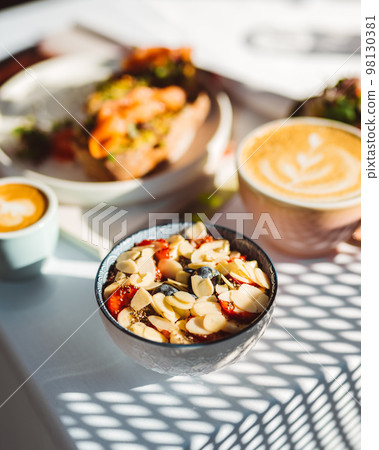 Bowl of oatmeal porridge with strawberry and almond flakes on vintage table at cafe 98130381