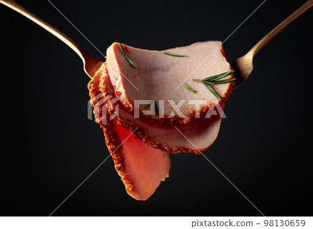 Spicy sliced ham on forks. 98130659