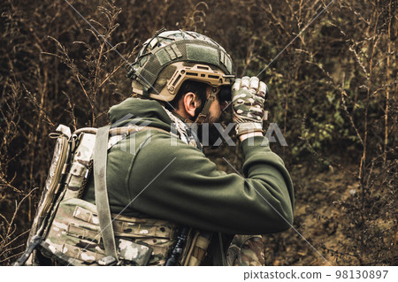Soldier with binocular investigating the place 98130897