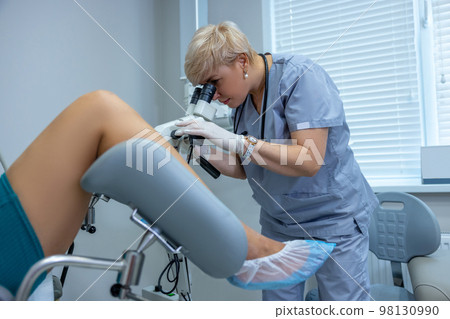 Experienced gynecologist doing colposcopy to a woman 98130990