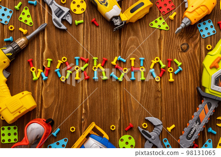 Toy tools, bolts and nuts with text WORKSHOP on wooden background 98131065