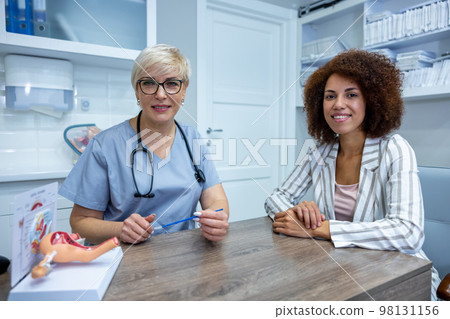 Expericenced gynecologist showing the anatomical model to junior colleague 98131156
