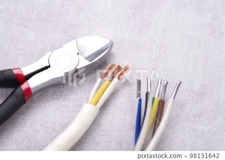 Electric cables without insulation and wire cutters on a gray table Electric cables without insulation and wire cutters on a gray table 98131642