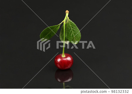 Cherry with green leaf isolated on black background, side view. Extrem close-up. Cherry with green leaf isolated on black background, side view. Extrem close-up. 98132332