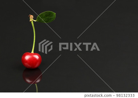 Cherry with green leaf isolated on black background, side view. Extrem close-up. Cherry with green leaf isolated on black background, side view. Extrem close-up. 98132333