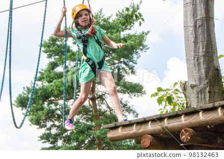 adventure climbing high wire park - people on course in mountain helmet and safety equipment. High quality photo 98132463