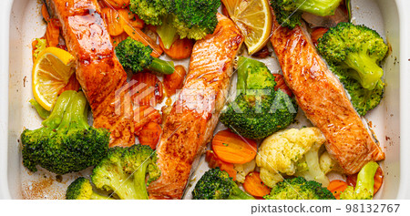 Top view close up of healthy baked fish salmon steaks, broccoli, cauliflower, carrot in casserole dish. Cooking a delicious low carb dinner, healthy nutrition concept. 98132767