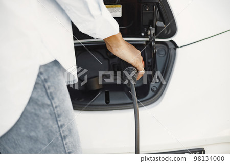 Islam black girl charging electro car. Eco car. 98134000