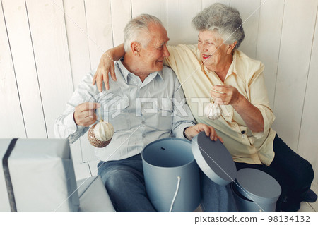 Grandparents at home. Old people with presents. Senior in a blue shirt. Grandparents at home. Old people with presents. Senior in a blue shirt. 98134132