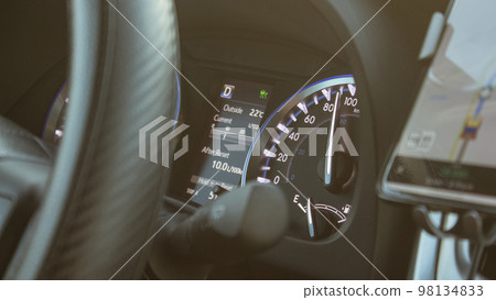 Illuminated speedometer dashboard and steering wheel of a modern car in a sun flare. Man is driving vehicle with sun flare from the outside in the sunny day. Illuminated speedometer dashboard and steering wheel of a modern car in a sun flare. Man is driving vehicle with sun flare from the outside in the sunny day. 98134833