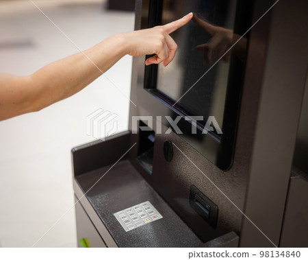Faceless woman using touchscreen ATM.  98134840