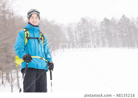 Man walking in snowy mountains with snowshoes 98135218