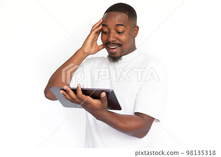 Surprised young man reading news on digital tablet Surprised young man reading news on digital tablet 98135318